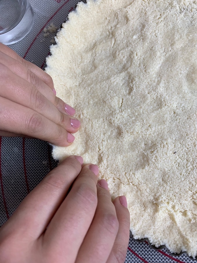 Pressing dough mixture onto removable bottom tart pan.