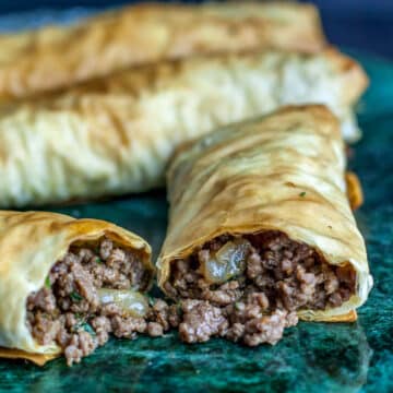 A photo of beef burek on a green marble platter.