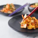 Korean kimchi on a black plate with chop sticks.