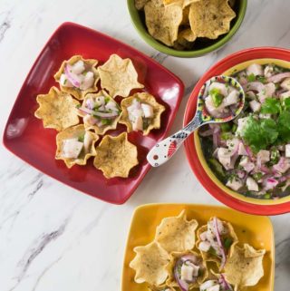 A red serving plate with a large bowl of tilapia ceviche.