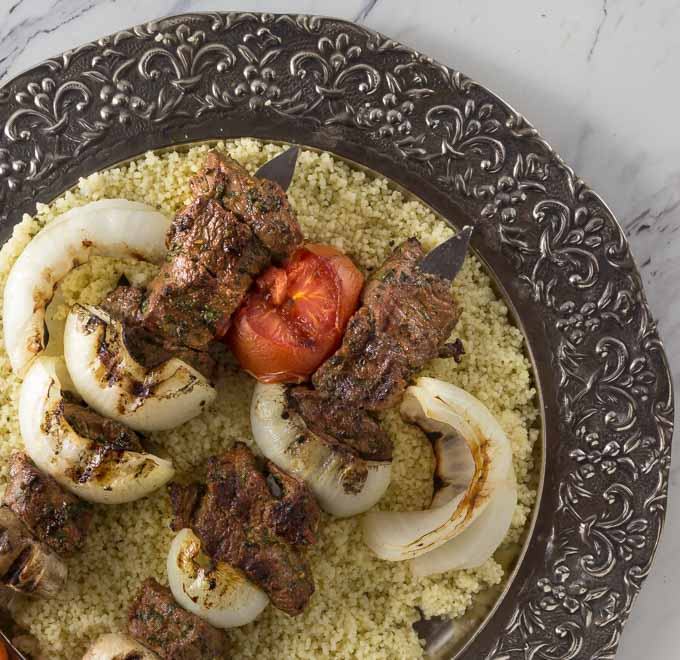 Beef kebab on a silver platter with couscous. 