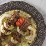 Moroccan style grilled beef kebab with tomato, onion and couscous.