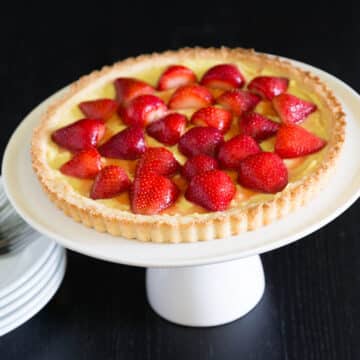 A strawberry tart on a white serving plate.