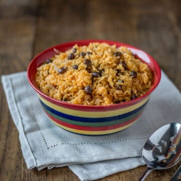 A photo of arroz con gandules in a bowl with a napkin and serving spoon.
