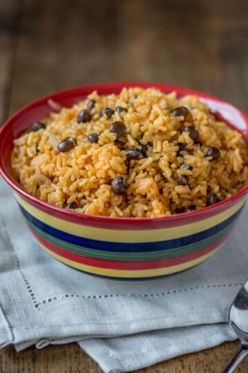 A photo of arroz con gandules in a bowl with a napkin and serving spoon.