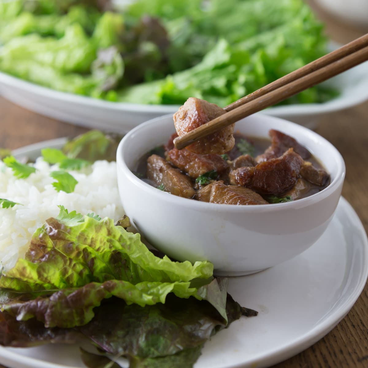 A photo of Vietnamese braised coconut pork, thit kho tau, in a white bowl.
