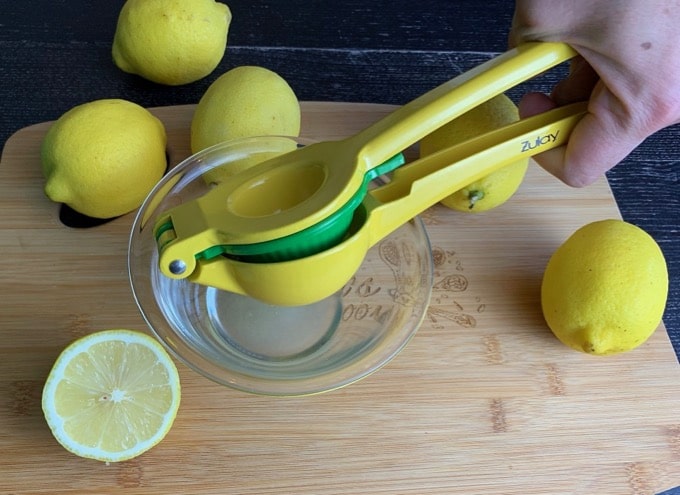 A photo of a Zulay lemon lime squeezer squeezing a lemon into a bowl.
