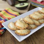 A plate with avocado and black bean empanadas.