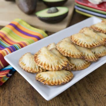 A plate with avocado and black bean empanadas.