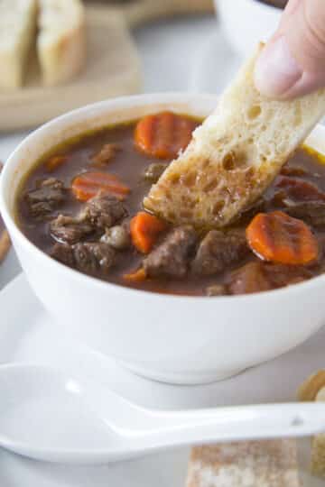 A photo of Vietnamese beef stew, bo sot vang, in a white bowl with bread.