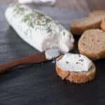 A photo of goat cheese on a cutting board with sliced baguette.