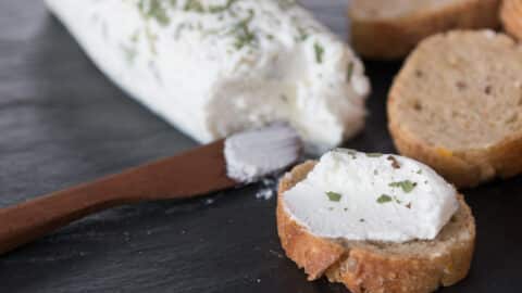 A photo of goat cheese on a cutting board with sliced baguette.