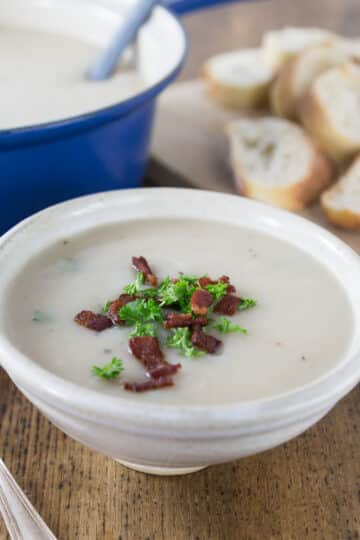 A bowl of Irish potato soup in a ceramic bowl with bacon and parsley on top.