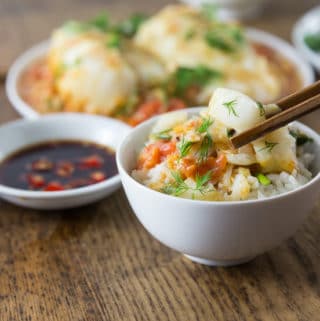 A photo of Vietnamese tomato fish with dill in a white bowl with rice.