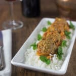 A photo of North African lamb meatballs in a white plate with rice and mint leaves.