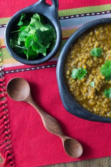 A photo of misir wot red lentil stew in a black bowl with cilantro.