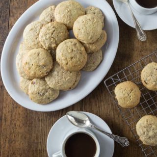 A photo of hermit cookies on a white plate with two cups of coffee.
