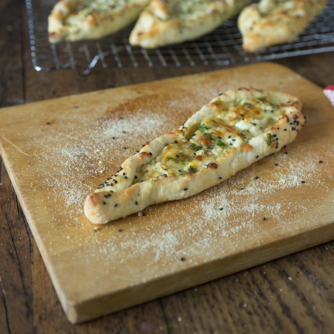 A photo of a Turkish pide on a cutting board after baking.