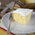 A photo of a piece of tres leches cake on a plate with a fork.