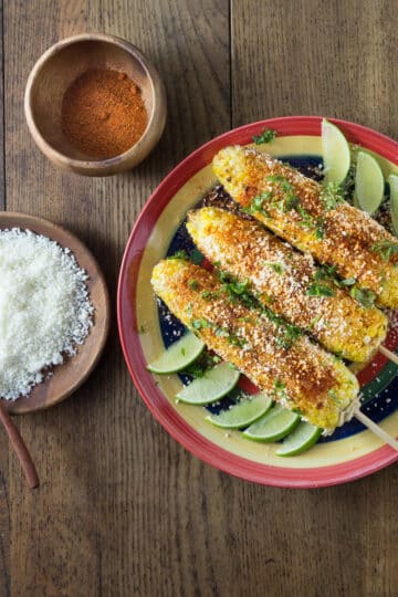A photo of Mexican elote on a plate with limes.