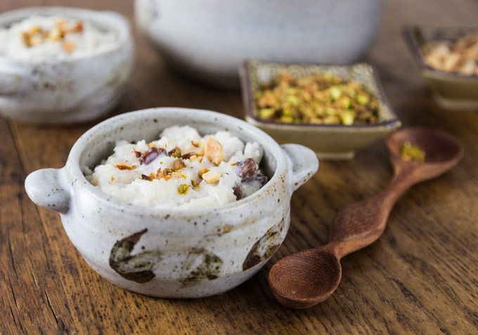 A photo of a gray bowl with kheer and a wooden spoon.