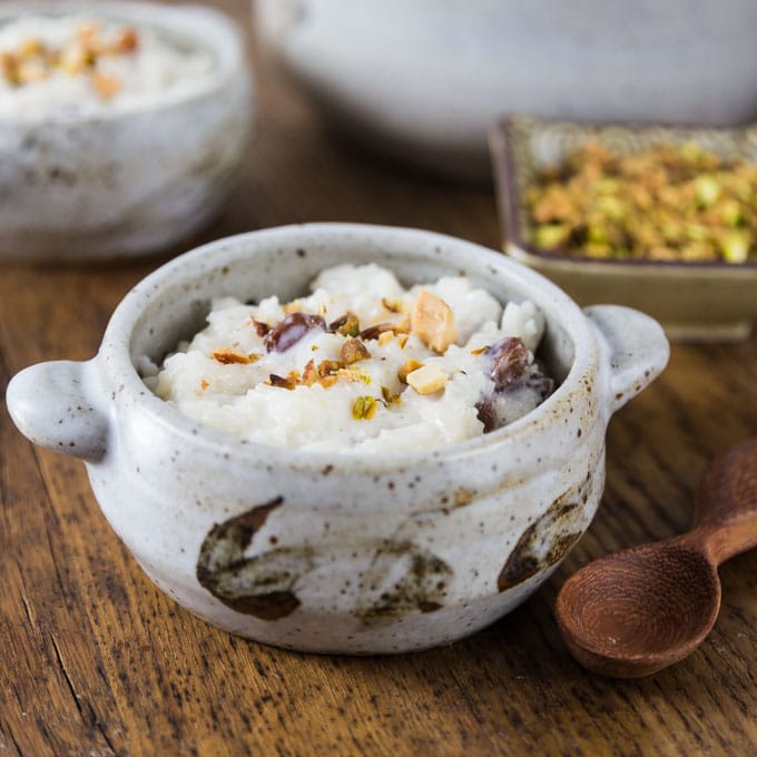 A photo of kheer and in bowl with nuts on top.