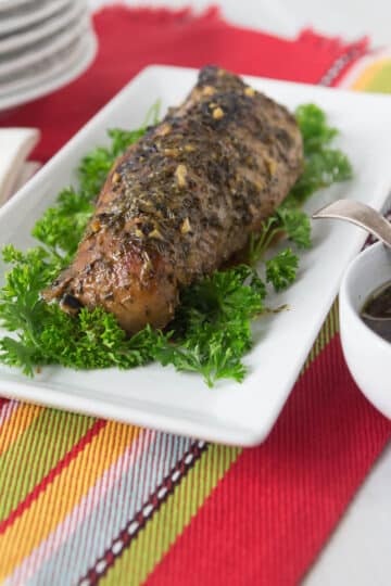 A photo of a pork loin marinated in tamarind sauce on a white plate.