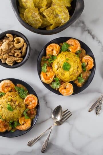 An overhead photo of shrimp mofongo on black plates.