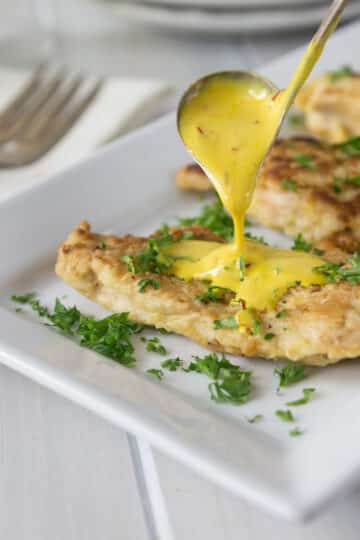 Chicken in creamy saffron sauce on a white plate.