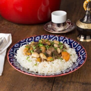 A photo of Turkish lamb stew on a blue plate with rice.