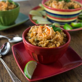 A bowl on a plate with shrimp asopao