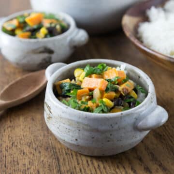 A photo of West African peanut stew in a gray ceramic bowl with rice.