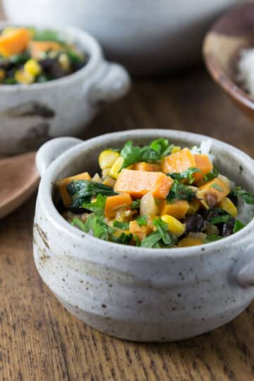 A photo of West African peanut stew in a gray ceramic bowl with rice.
