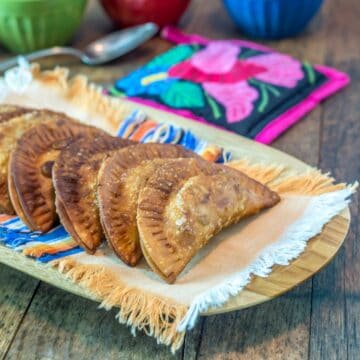 A photo of black bean and plantain empanadas in a wooden platter.