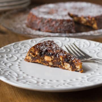 A photo of Italian panforte on a white plate with a fork.