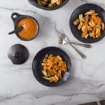 A photo of Spanish patatas bravas on two black plates with two forks.