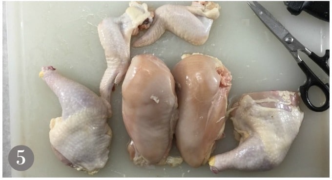 A photo of a cut up whole chicken in 6 pieces.