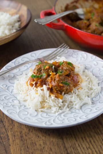 A photo of Persian meatballs on a plate with rice and a fork.