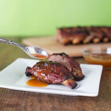 A photo of mango habanero ribs on a white plate with rib sauce.