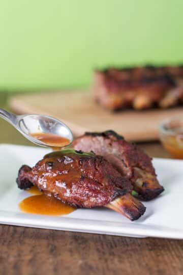 A photo of mango habanero ribs on a white plate with rib sauce.