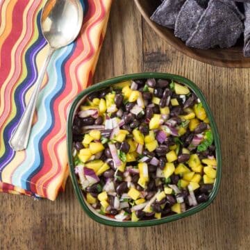 A overhead photo of mango black bean salsa in a bowl with a napkin and spoon.