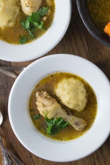 An overhead photo of African pepper soup with fufu in white bowls.