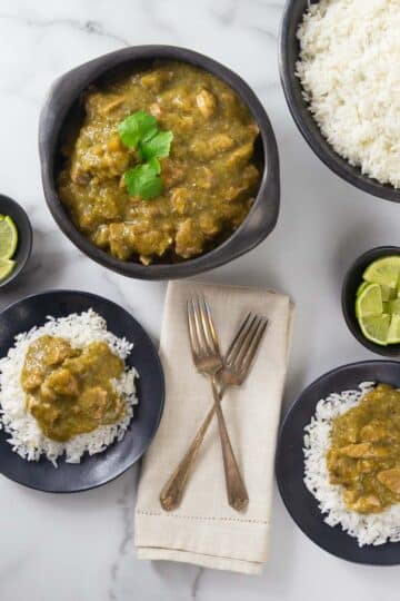 A overhead photo of pork chili verde in a bowl with plates of rice.