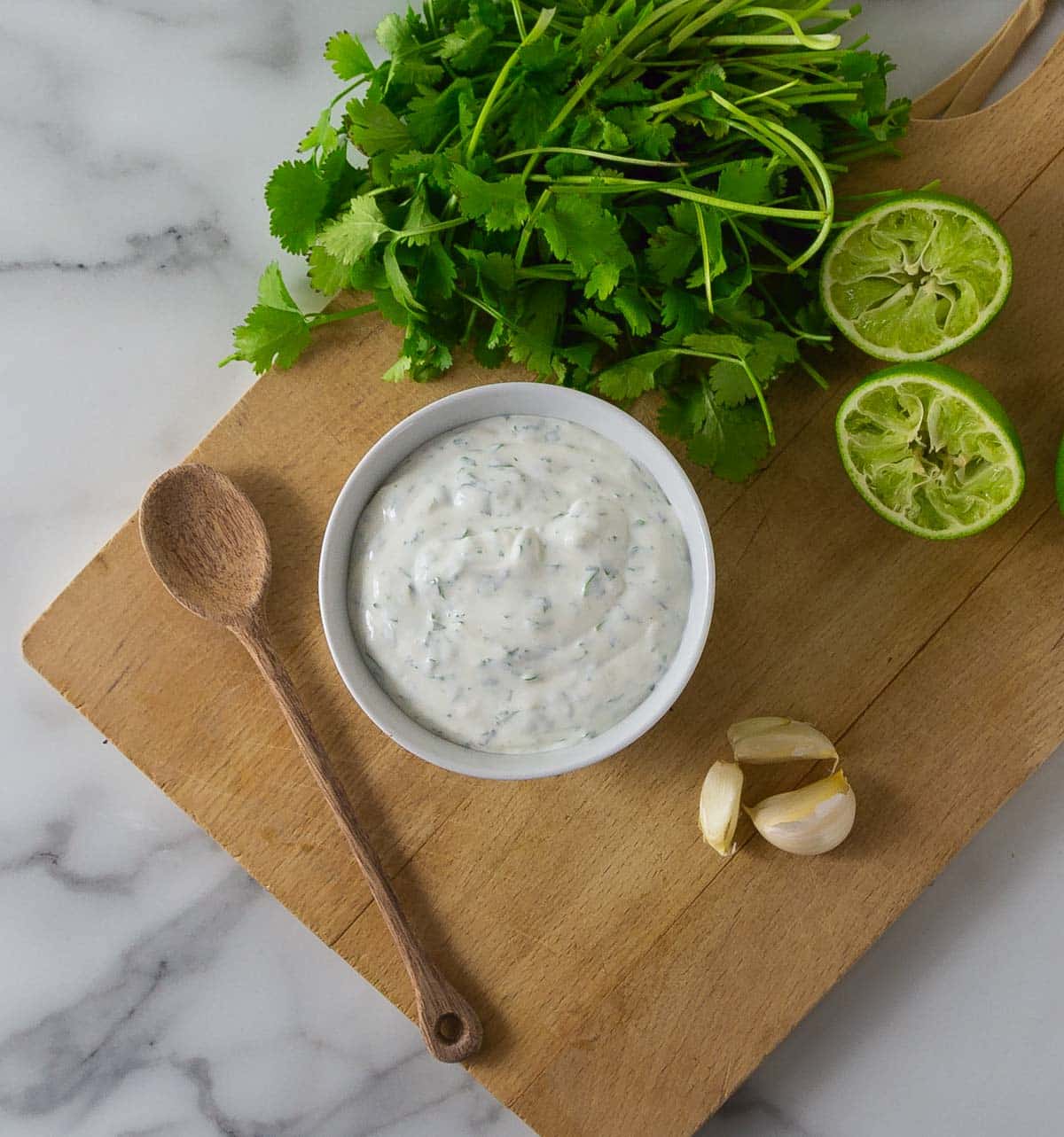 A photo of cilantro lime crema in a while bowl sitting on a cutting board.