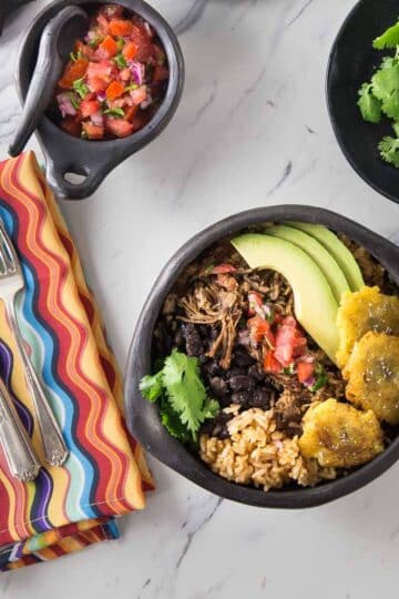 A photo of a pork carnita bowl with pico de gallo.