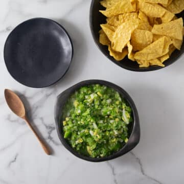 An overhead photo of tomatillo avocado salsa in a black bowl.