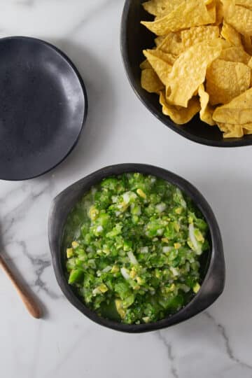 An overhead photo of tomatillo avocado salsa in a black bowl.