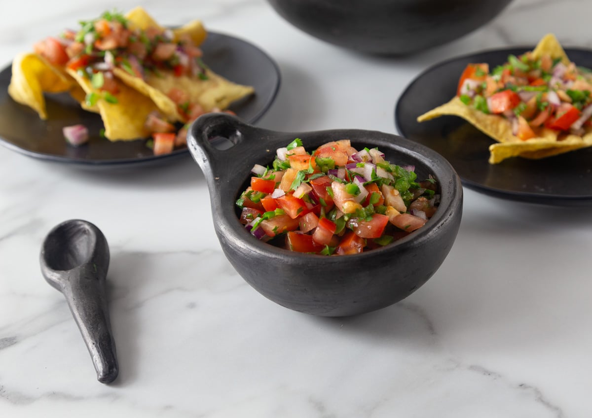 A photo of pico de gallo in a black ceramic bowl.