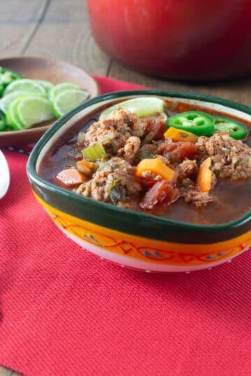 A photo of Mexican albondigas in a green and yellow bowl.