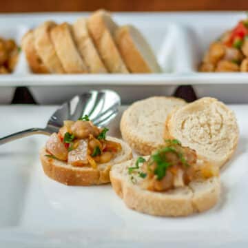 A photo of Spanish style garbanzo bean tapa with sliced baguette.